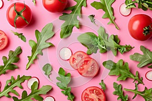 Fresh arugula, lettuce, radish, tomato salad ingredients on pink background, healthy veggies display