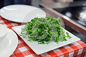 Fresh arugula salad on white square plate