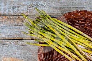 Fresh asparagus in brown basket on wood table
