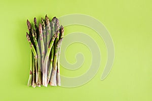 Fresh asparagus bundle on vibrant green background. Top view