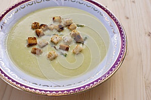 Fresh asparagus cream soup on wooden background overhead shoot.