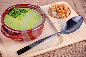 Fresh asparagus creamy soup and ingredients on a wooden table.