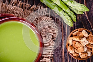 Fresh asparagus creamy soup and ingredients on a wooden table.