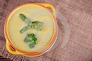 Fresh asparagus creamy soup and ingredients on a wooden table.