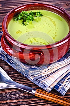 Fresh asparagus creamy soup and ingredients on a wooden table.