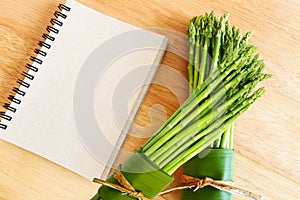 Fresh asparagus on wooden background and blank diary b