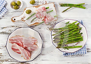 Fresh asparagus wrapped in bacon on a wooden table.