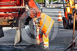 The fresh asphalt feed mechanism unloads it from the car for subsequent repair of the road section