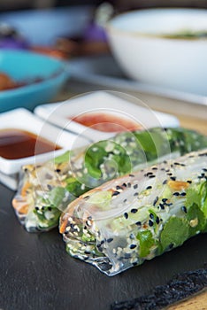 Fresh assorted Asian spring rolls with shrimps, vegetables, fruit over rustic concrete background