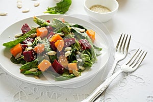 Fresh autumn salad with marinated pumpkin and beetroot, spinach leaves,olive oil, sesame and pumpkin seeds