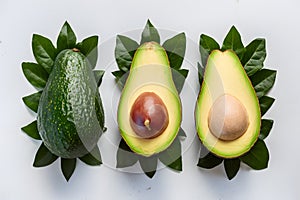 Fresh avocado and green leaves arranged on a white background