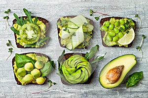 Fresh avocado toasts with different toppings. Healthy vegetarian breakfast with rye wholegrain sandwiches.