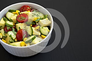 Fresh Avocado Tomato Salad in a bowl on a black surface, side view. Copy space