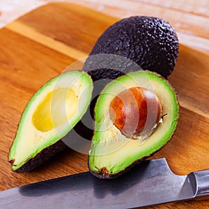 Fresh avocadoes and kitchen knife on cutting board