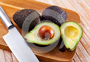 Fresh avocadoes and kitchen knife on cutting board