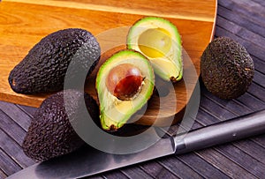 Fresh avocadoes and kitchen knife on cutting board