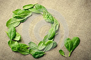 Fresh Baby spinach leaves on sackcloth background. Top view with copy space, round circle frame. Love, Healthy, Ecology