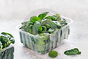 Fresh baby spinach in a plastic package on table. Green salad, baby spinach leaves box