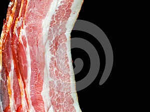 Fresh bacon with meat and fat on a black background close-up