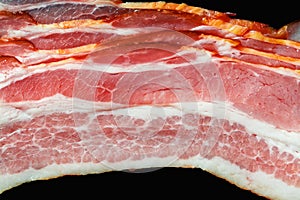 Fresh bacon with meat and fat on a black background close-up