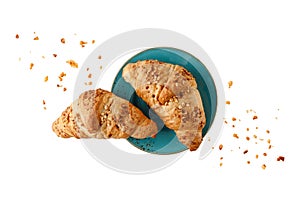 Fresh baked almond nuts croissants with crumbs on vintage blue green plate isolated on white background