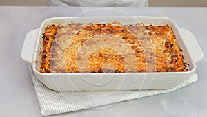 Fresh baked beef lasagna in baking dish close up on kitchen table