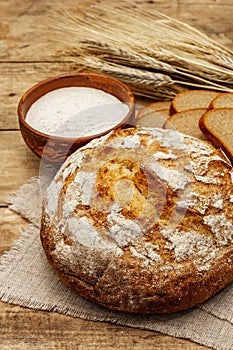 Fresh baked bread with wheat ears and a bowl of flour