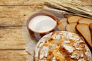 Fresh baked bread with wheat ears and a bowl of flour