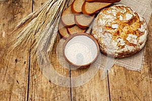 Fresh baked bread with wheat ears and a bowl of flour