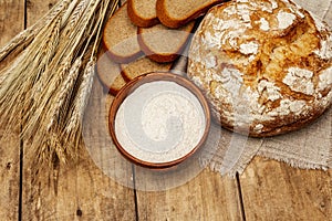 Fresh baked bread with wheat ears and a bowl of flour