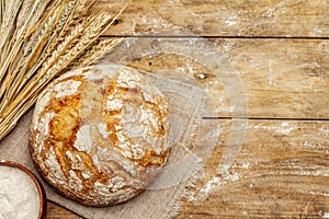 Fresh baked bread with wheat ears and bowl of flour