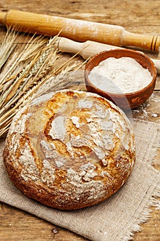 Fresh baked bread with wheat ears, bowl of flour and rolling pins