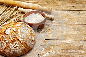 Fresh baked bread with wheat ears, bowl of flour and rolling pins