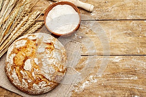 Fresh baked bread with wheat ears, bowl of flour and rolling pins