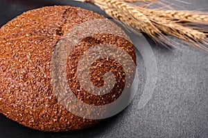 Fresh baked brown bread with ears and grains of wheat