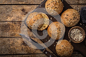 Fresh baked buns with sesame, sunflower and flaxseed, wooden background