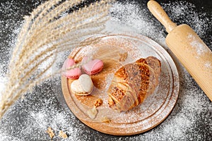 Fresh baked butter crushed nuts breakfast croissant, french herz macarons  and crumbs  on wooden board