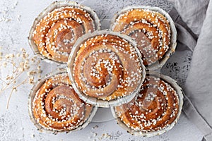 Fresh baked cinnamon buns rolls with grey linen napkin on grunge stone table background. Traditional swedish sweet pastry