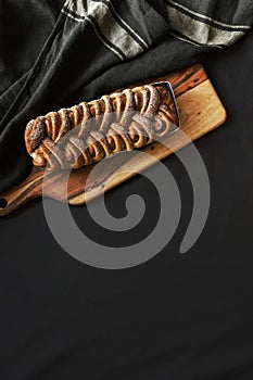 Fresh baked cinnamon roll bread on wooden board with black background
