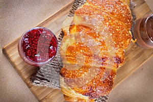 Fresh baked croissants with raspberry jam and chocolate on wooden chopping board