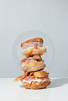 Fresh baked eclairs and profiteroles filled with fresh cream and salmon. On white background.