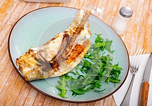 Fresh baked fish sea bass with arugula photo