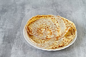 Fresh baked french crepes or Russians blinis on grey background