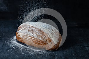 Fresh baked gluten-free grey bread. Fresh bread on table close-up. Food in motion concept. Flour fly on bread in kicthen. Eco food