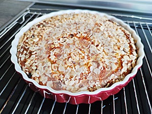 Fresh baked golden apple pie in red dish in oven at kitchen