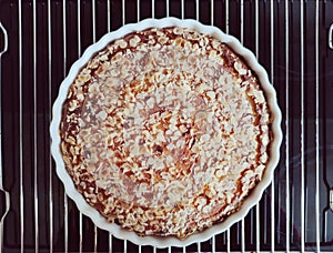 Fresh baked golden apple pie in red dish in oven at kitchen