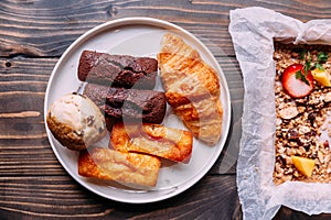 Fresh baked goods on white dish including scone, croissant, financier and chocolate financier