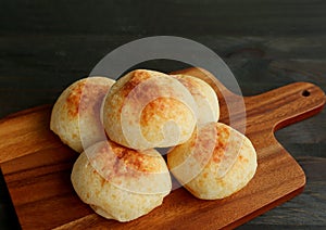 Fresh baked homemade Brazilian cheese breads or Pao de Queijo on a wooden breadboard