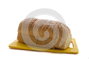 Fresh baked homemade bread and sliced bread on plastic yellow cutting board isolated.