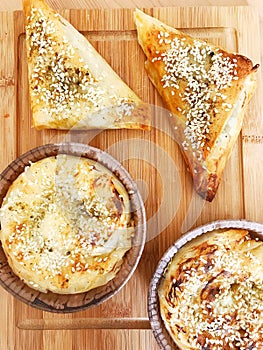 fresh-baked homemade fila puff pastry cheese patties on a wooden table.